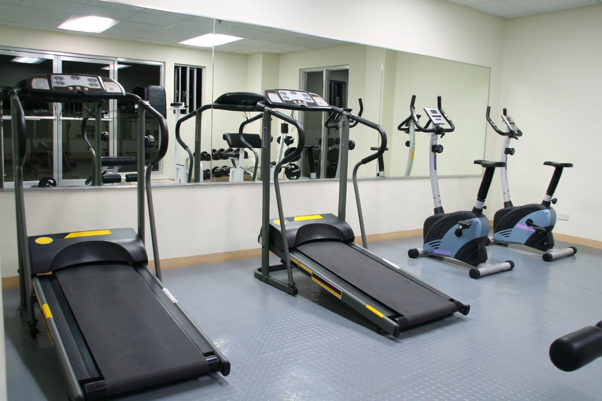 A gym with treadmills and a workout bike next to a mirror wall